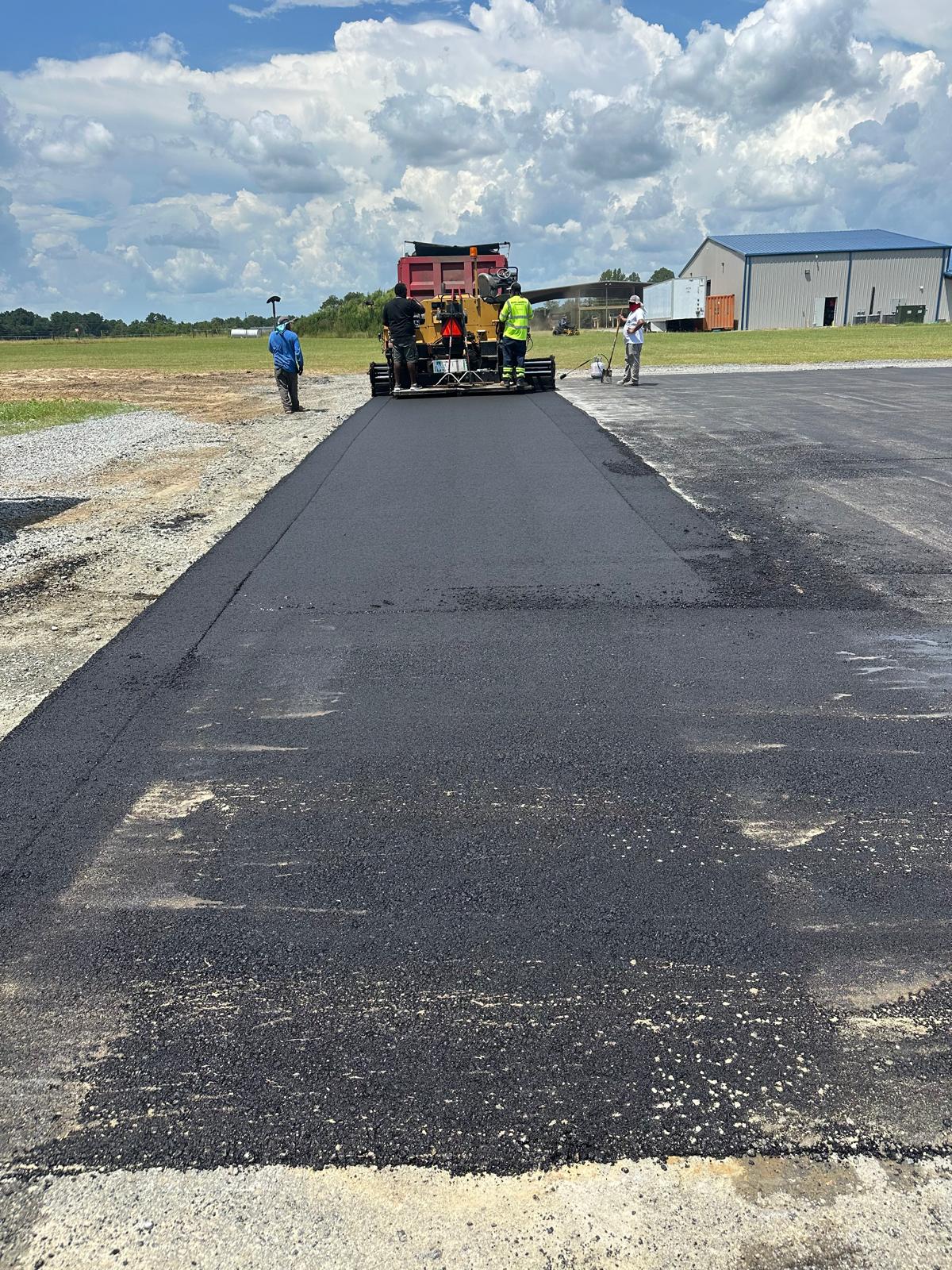 Norka crew laying fresh asphalt with a paver on a commercial site