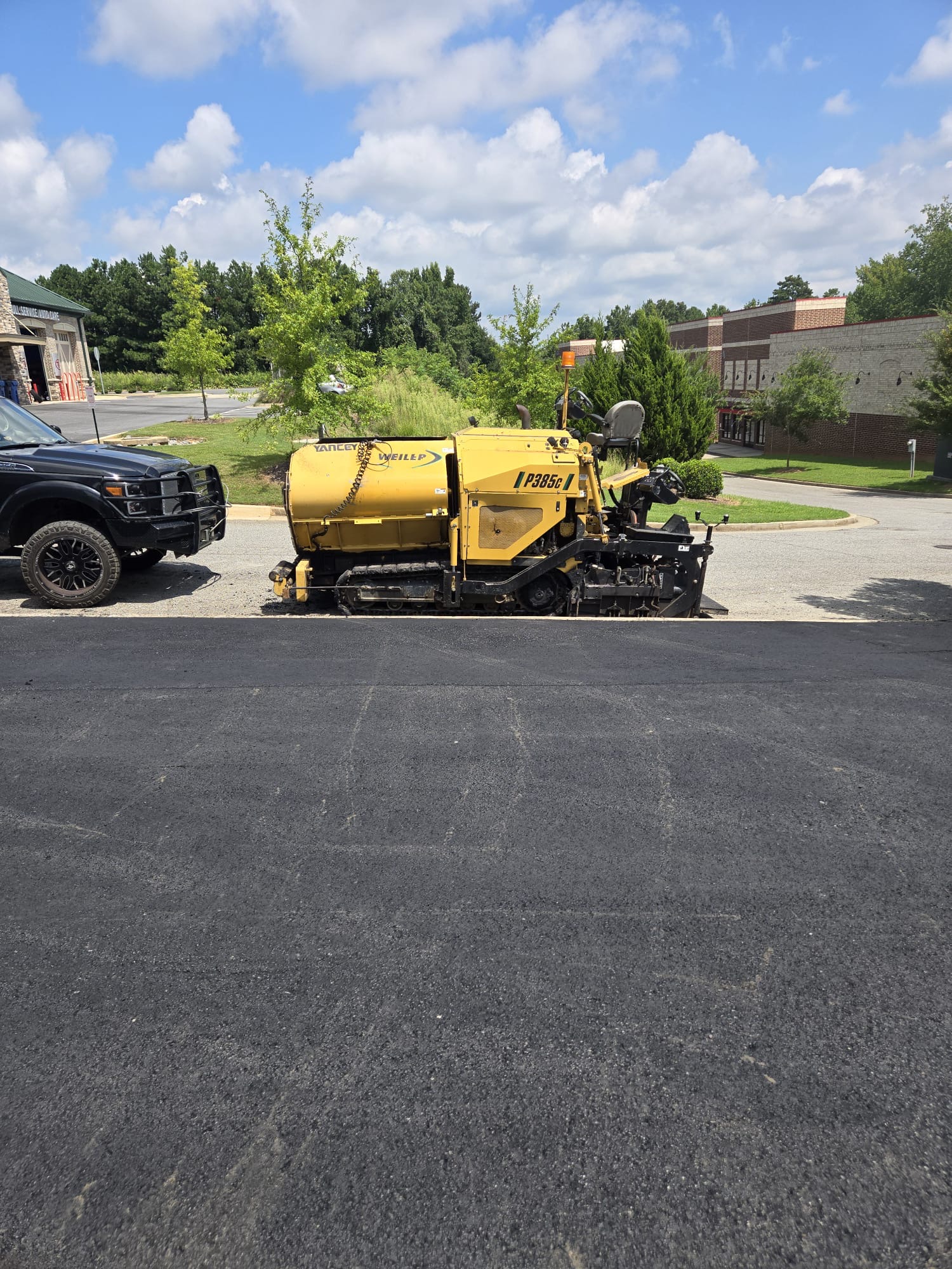 Asphalt paver parked on a freshly finished commercial lot